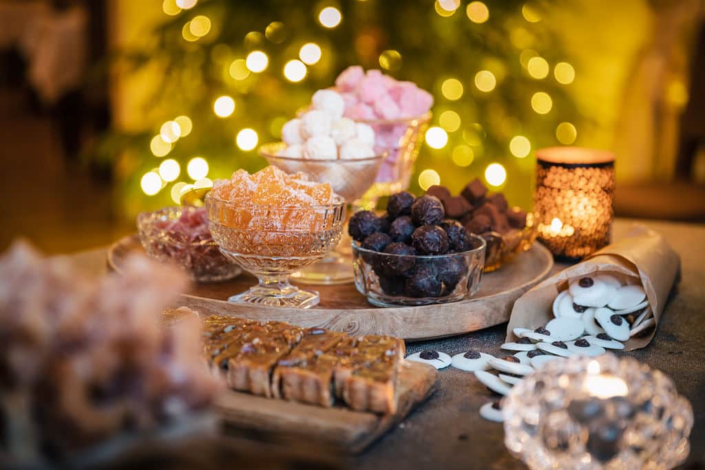 Julgodis med ljus i bakgrunden Julbord med belysning på efterrätterna